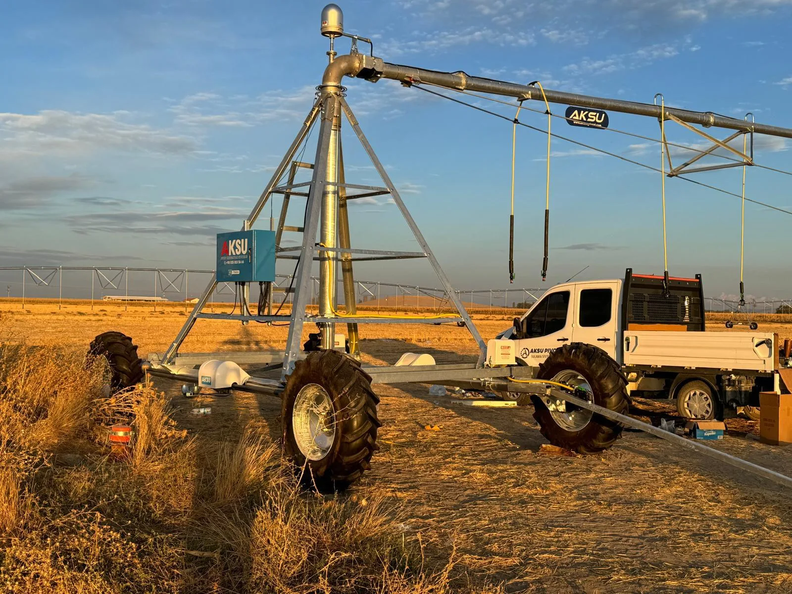 An AksuPivot pivot point and span at sunset on a Konya field, with a pickup parked alongside