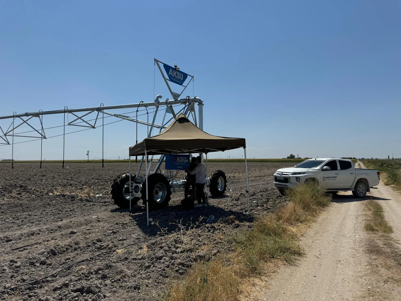 An AksuPivot machine on a worked Konya field with a canopy and a company flag beside it