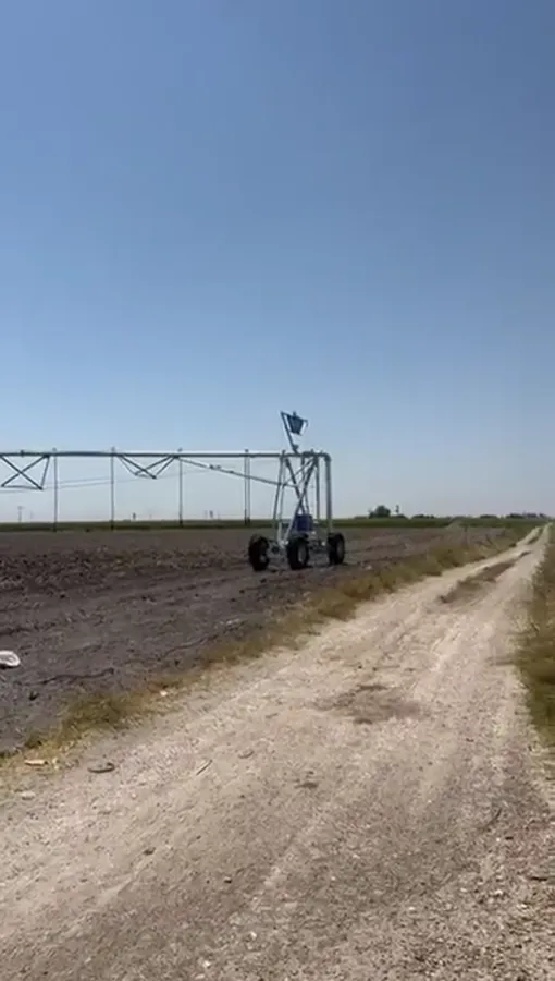 An AksuPivot pivot point on its wheels beside a green crop in Konya